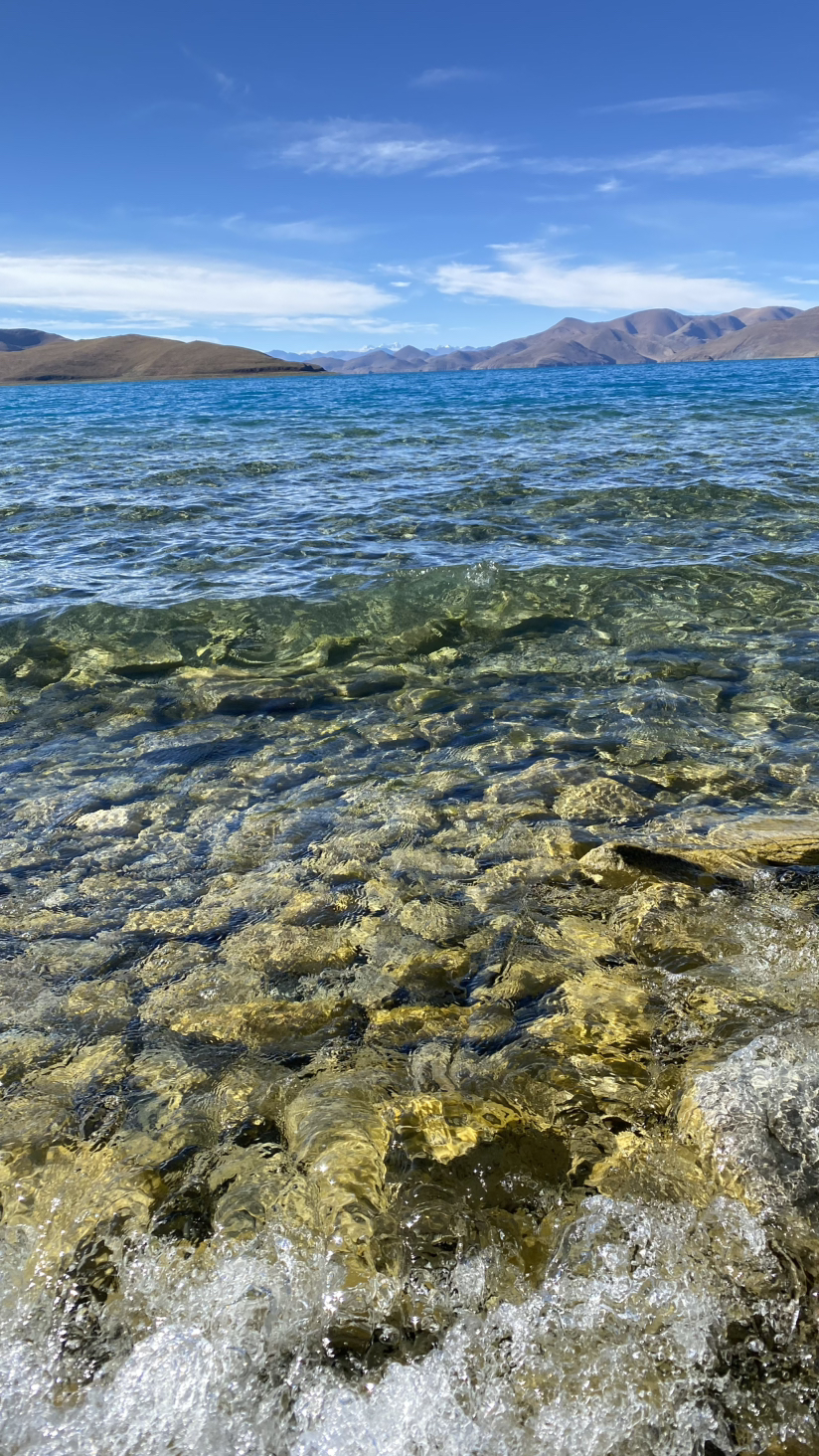 羊卓雍措湖碧蓝如镜，映衬雪山与草原，湖水波光粼粼，色彩变幻。这里宁静纯净，羊群悠闲漫步，四周群山环绕，宛如天成画卷