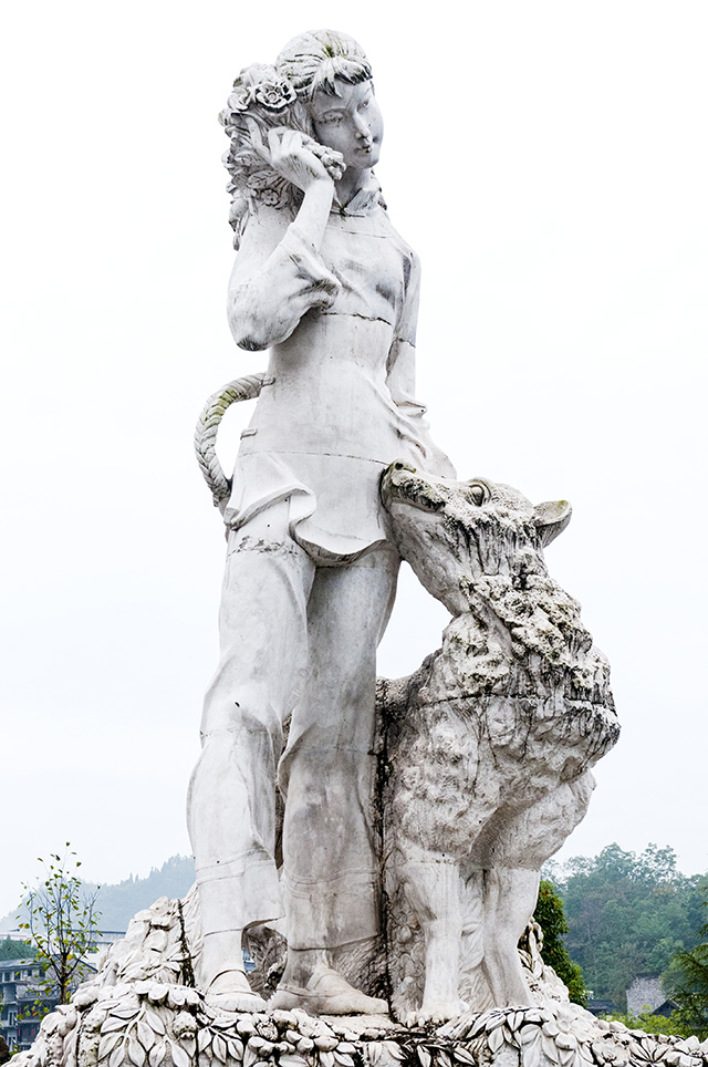 仰望翠翠雕塑,她牵着大黄狗,右手拿着花,怎么看都象是在拔打手机,她是